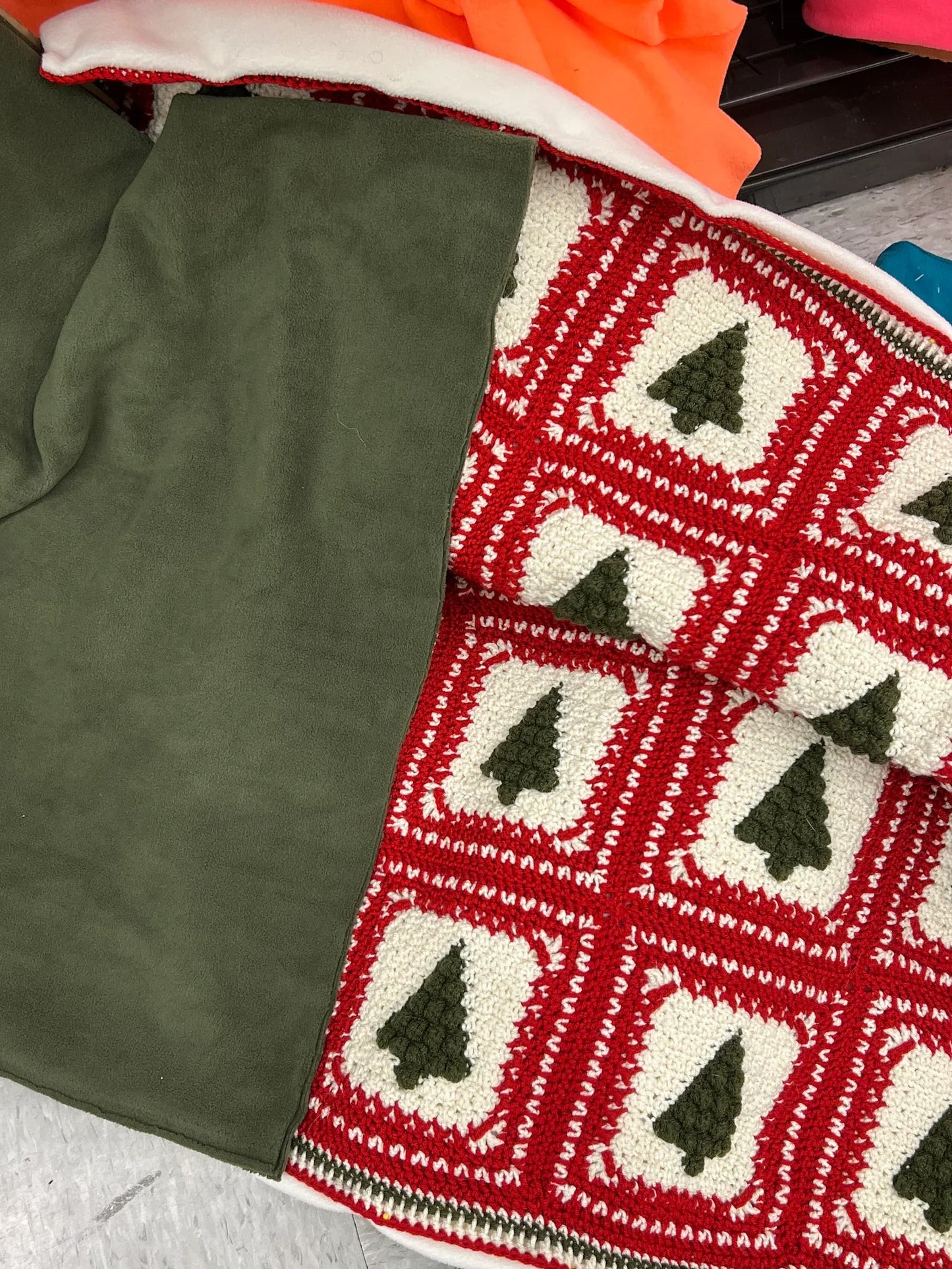 Finished Christmas Tree crochet pattern blanket folded beside Christmas decorations.