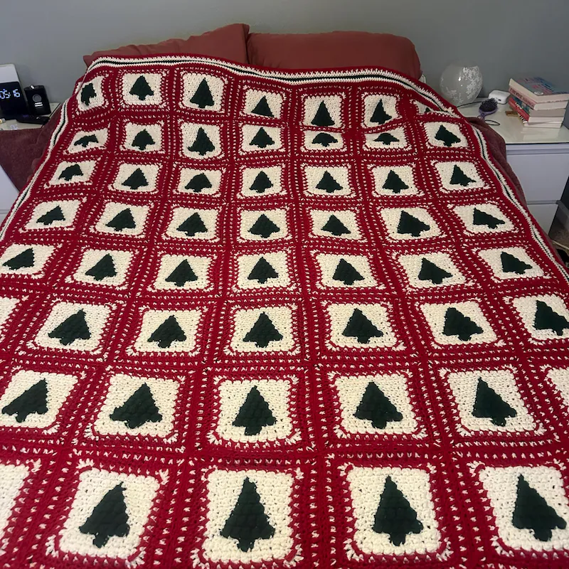 Handmade blanket made with the Christmas Tree crochet pattern displayed on a cozy couch.