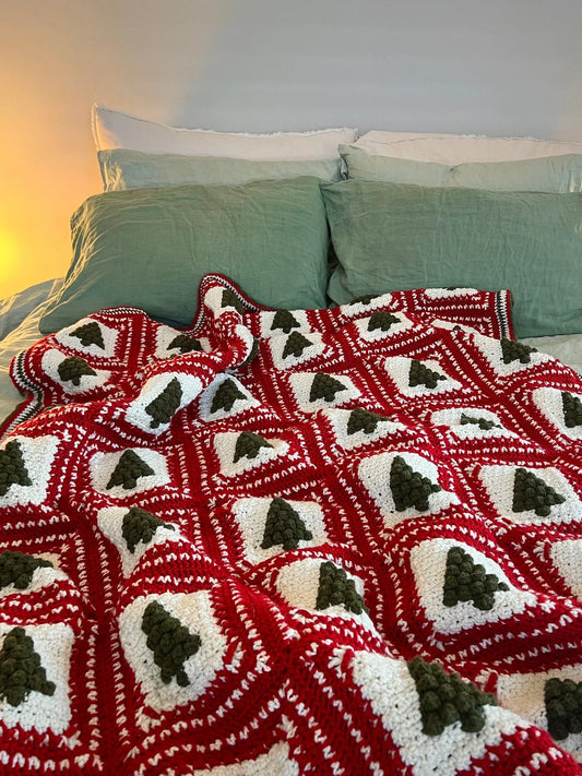 Handmade blanket made with the Christmas Tree crochet pattern displayed on a cozy couch.