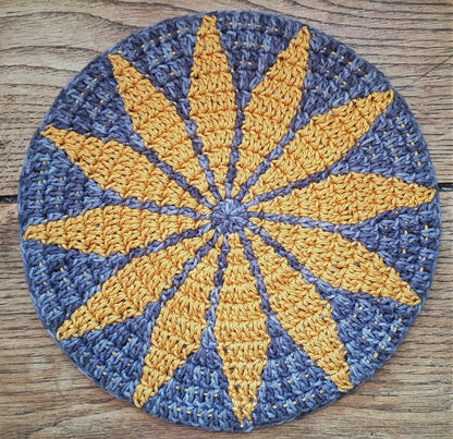 Round crocheted mat with yellow star pattern on a wooden surface