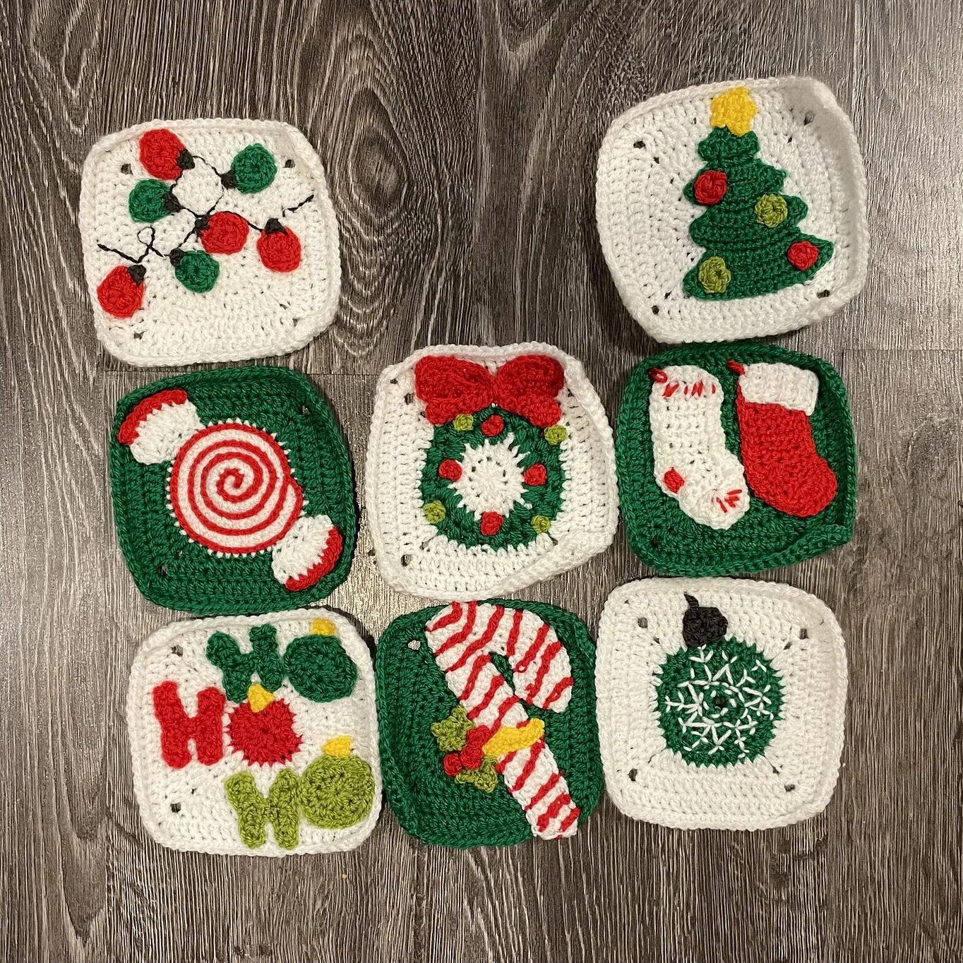 Set of crocheted Christmas-themed granny squares on a wooden surface