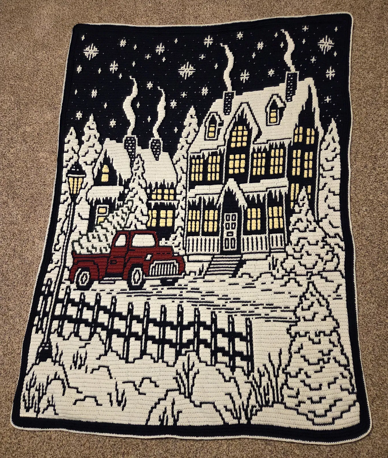 Handmade christmas crochet blanket with festive winter village on a brown surface