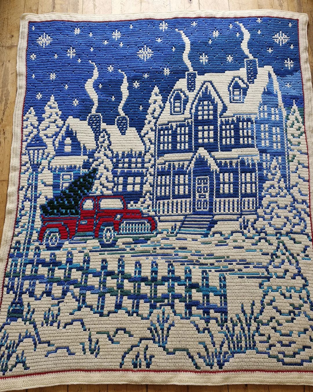 Cozy christmas crochet blanket with village houses and winter scene