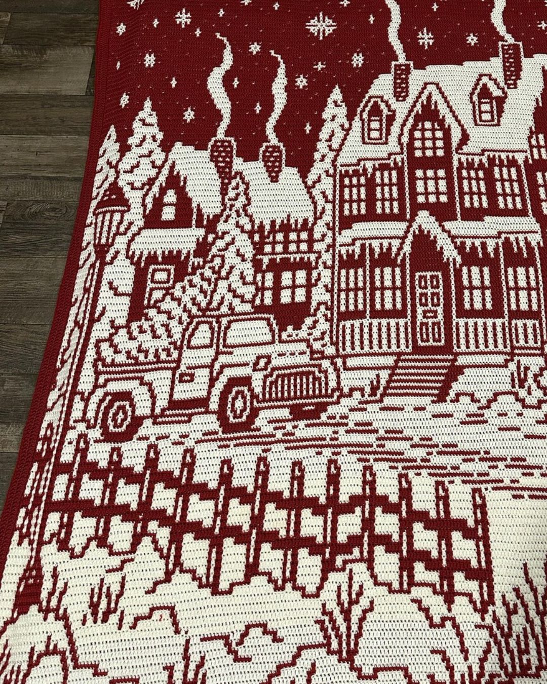 Handmade christmas crochet blanket with a winter village scene featuring houses and a truck.