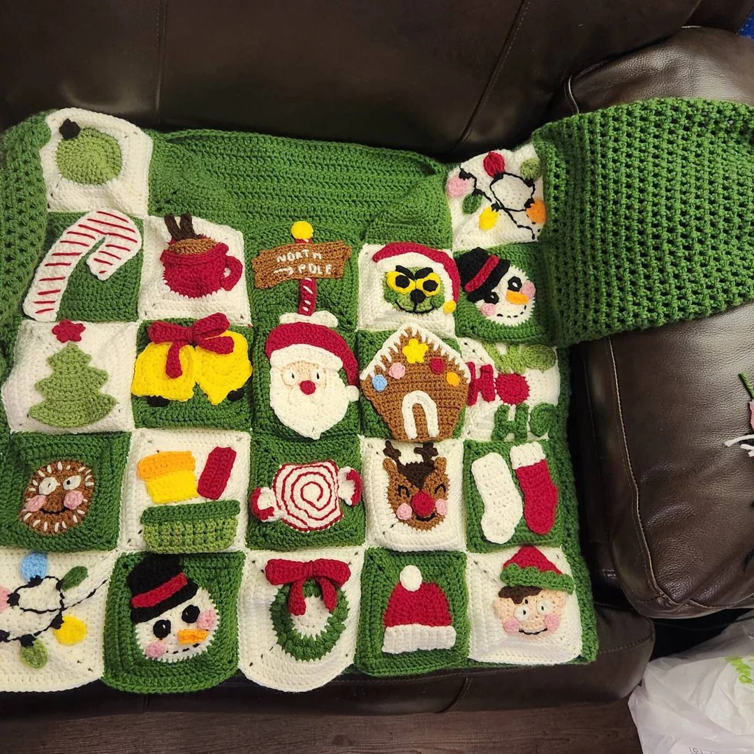 Crocheted Christmas-themed sweater on a brown leather couch.