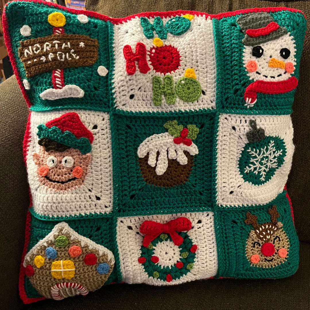 Crocheted Christmas-themed pillow with various festive granny square designs.