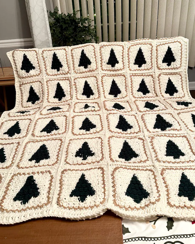Finished Christmas Tree crochet pattern blanket folded beside Christmas decorations.