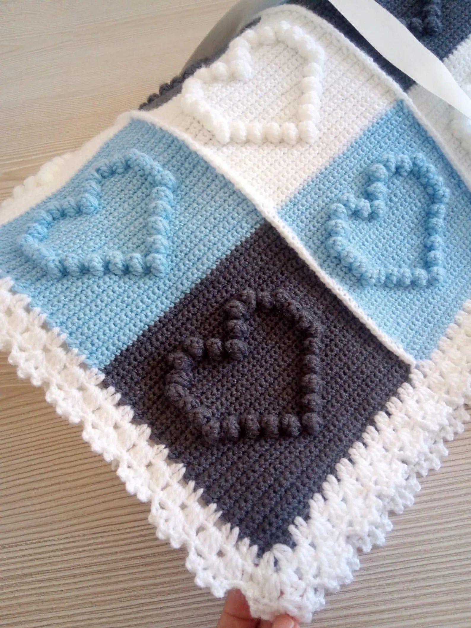 Crocheted baby blanket with blue, white, and gray squares